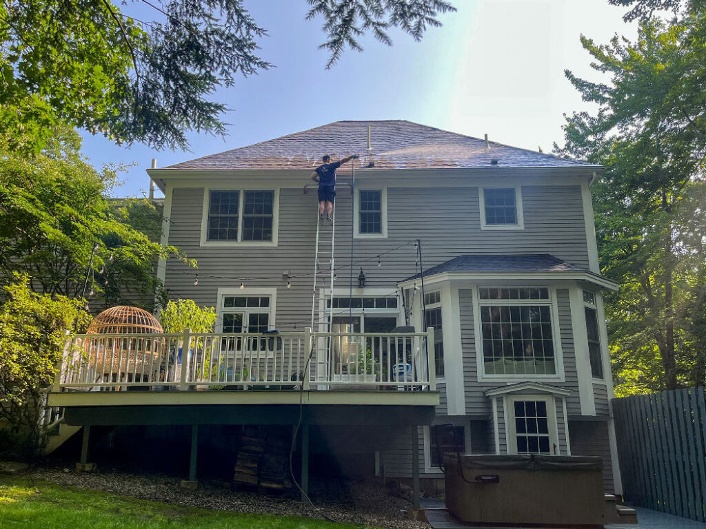 CleanME owner on ladder power-washing a residential home in southern Maine