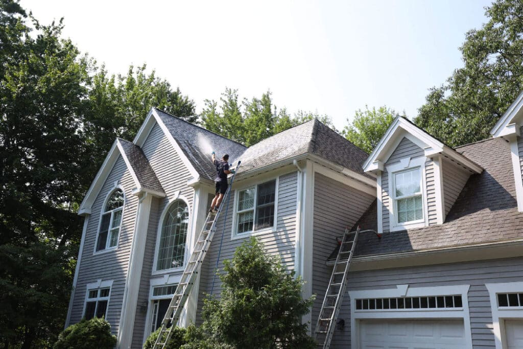 CleanME owner on ladder exterior cleaning a residential home in southern Maine